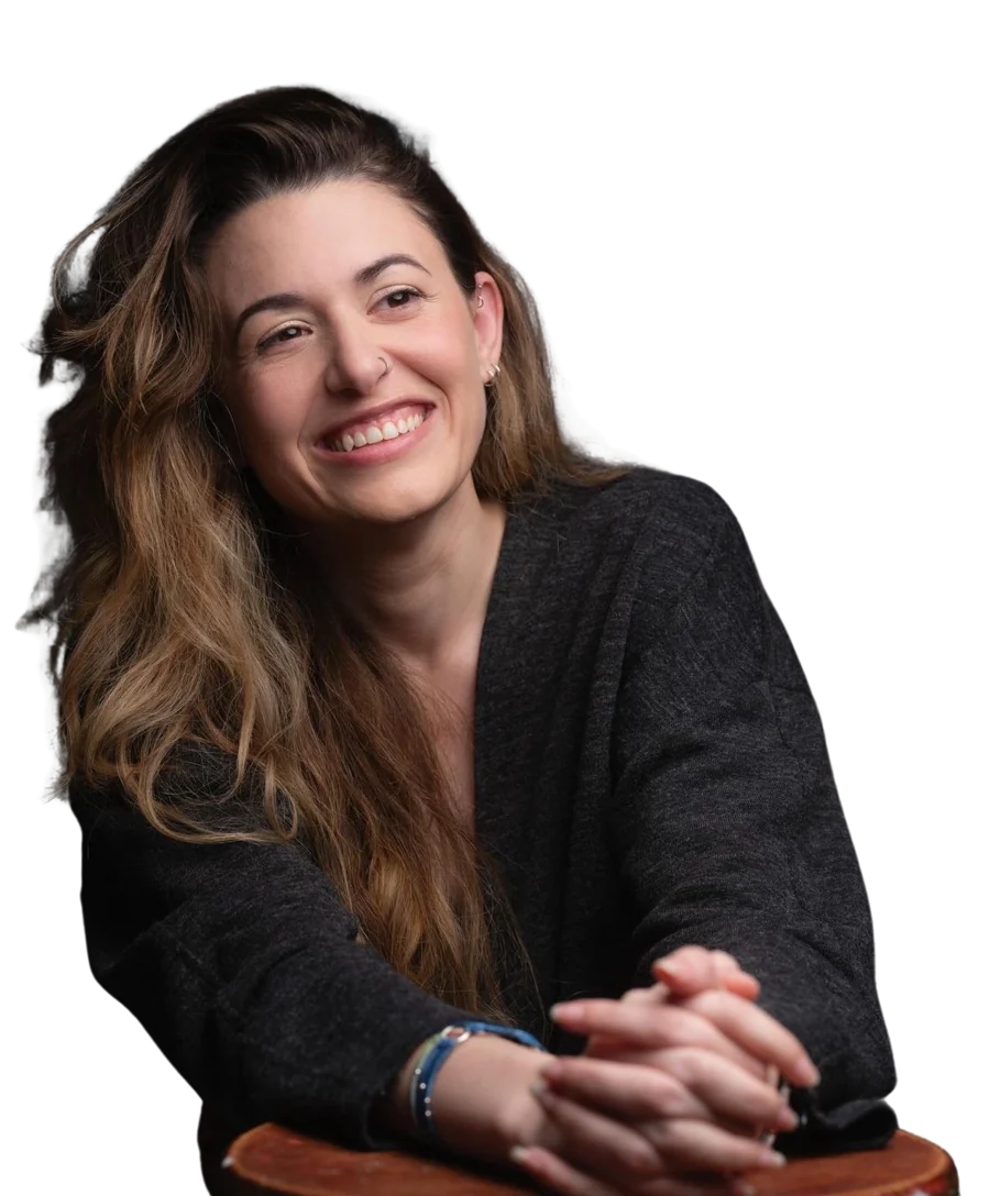 Nico Hughes smiling, with her hands resting on the back of a chair